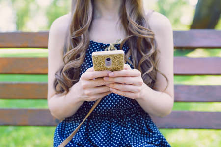 Cropped closeup photo of slim lovely pretty attractive teen lady user holding telephone in golden case in hands reading latest fresh news sharing posts comments subscribe collect followersの写真素材