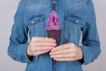 Cropped closeup photo of beautiful refreshing cold delicious bright icecream with black sugary cone isolated over grey backgroundの写真素材