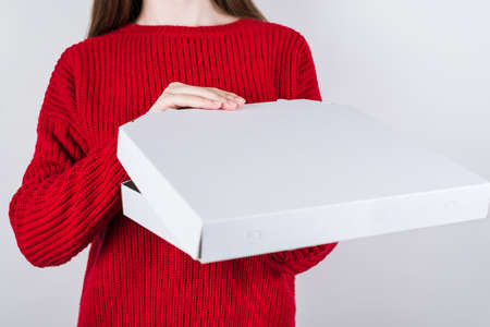 Quick delivery concept. Cropped close up photo of hands holding closed paper box with delicious pizza inside isolated grey backgroundの写真素材