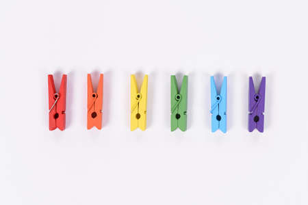 High angle view photo of six tiny wooden standing in line clothespins isolated white backgroundの写真素材