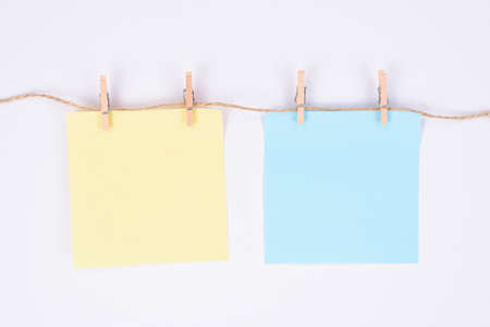 Photo of two square paper sheets hanging on rope isolated white color backgroundの写真素材