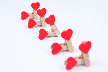 Group sex concept. Close up photo of clothespins with red hearts isolated on white background
