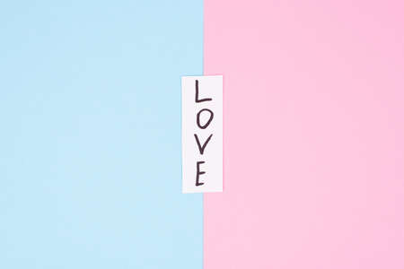 Vertical hand writing on colorful background. Close up top view photo of a memo with black letters word love isolated on divided backgroundの写真素材