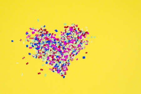 Top above close up overhead view of colorful heart made of confetti parts isolated over vibrant...