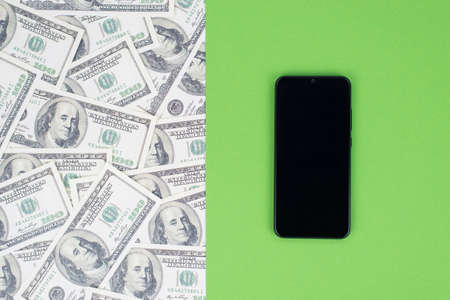 Top above flat lay close up view photo of smart phone with touch screen isolated on halved bright green and money print pattern template backgroundの写真素材