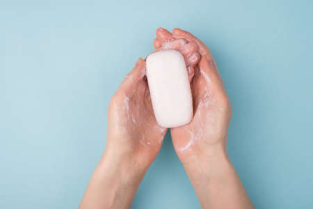 Above overhead close up view photo of teen girl using white solid cream soap for washing hands she has sensitive shin isolated over blue backgroundの写真素材