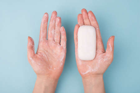 Above top overhead close-up view photo of hands using holding bar of soap and creamy soap isolated...