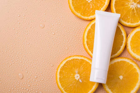 Antioxidant lifestyle wellness branding concept. Top above flatlay flat lay overhead close up view photo of blank cream tube lying on slices of orange fruit isolated beige background copy empty spaceの写真素材
