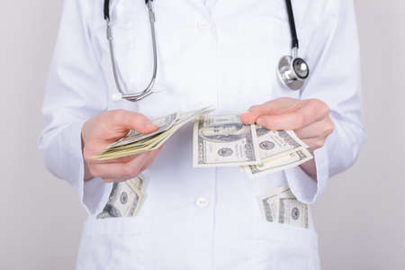 Cropped close up photo of woman doctor checking the number of banknotes in her pockets isolated over...