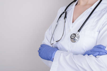 Cropped closeup photo of professional doctor in nitrile gloves standing with folded crossed arms isolated over grey background copy spaceの写真素材