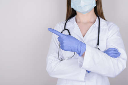 Cropped closeup photo of nurse pointing on empty blank space isolated over grey backgroundの写真素材