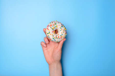 Photo of woman person hand holding rising up delicious nice beautiful single white with colorful sprinkles isolated over bright background with copy empty blank spaceの写真素材