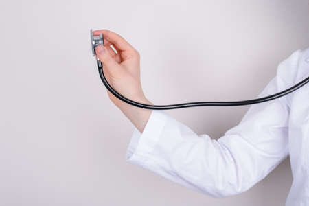 Body check medical examination body care concept. Side profile cropped closeup photo of stretched arm with stethoscope listening to patient breathing isolated over grey backgroundの写真素材