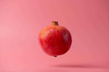 Photo of yummy delicious beautiful ripe bright pomegranate flying in air isolated over bright color background. Template pattern conceptの写真素材
