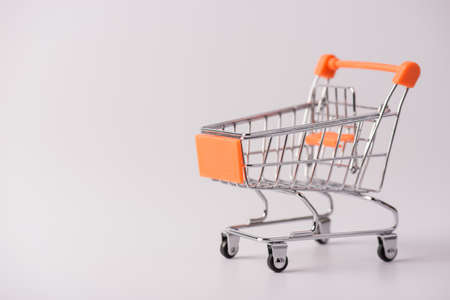 Shopping concept. Close up photo of small push cart with orange elements isolated over gray...