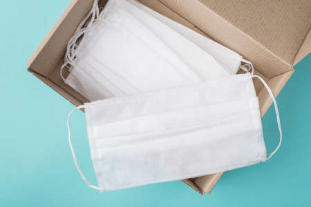 Coronavirus prevention concept. Top above overhead view photo of a box full of masks with one laying...