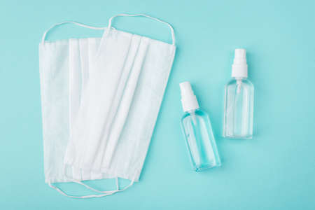 Healthcare during Coronavirus quarantine concept. Top above overhead view photo of masks and hand sanitizer bottle isolated on turquoise backgroundの写真素材