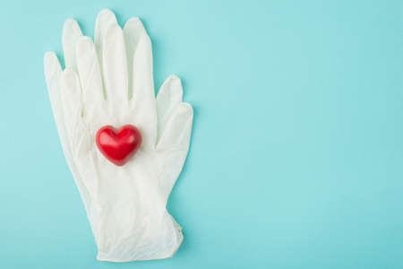 Top above overhead close up view photo of a heart on top of a pair of gloves isolated on turquoise backgroundの写真素材