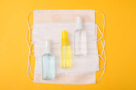 Essentials during COVID-19 outbreak. Top above overhead view close-up flat lay photo of masks and hand sanitizer bottles isolated on yellow backgroundの写真素材