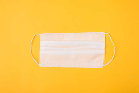 Top above overhead view close-up photo of a white mask isolated on yellow backgroundの写真素材