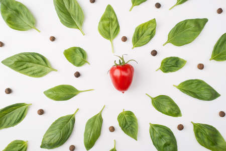 Top above overhead view photo of basil leaves, peppercorns and a cherry tomato isolated on white backgroundの写真素材