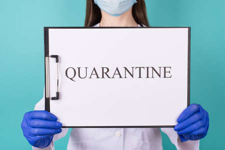 Close-up cropped photo of female doctor in gloves holding quarantine clipboard isolated on teal turquoise backgroundの写真素材