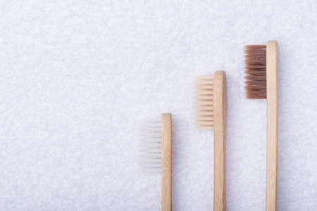 Top above overhead view photo of three bamboo eco-friendly toothbrushes isolated on white towel...