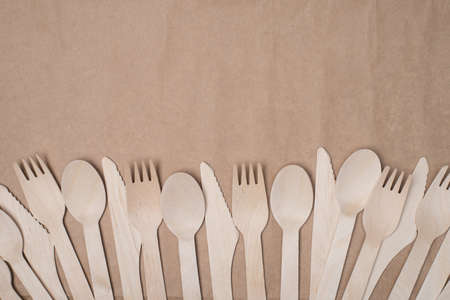 Sustainable cutlery concept. Top above overhead view photo of a row of wooden cutlery isolated on craft paper background tableの写真素材