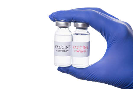 Coronavirus treatment concept. Close-up cropped photo of doctor holding two vials of COVID-19...