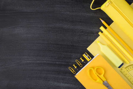 Bright school and office stationery concept. Top above overhead view photo of yellow stationery isolated on blackboard with empty blank copyspaceの写真素材