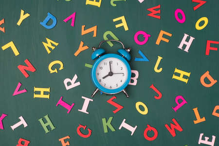 Task deadline concept. Top above overhead view photo of blue clock isolated on greenboard with colorful lettersの写真素材