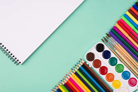Painting supplies concept. Top above overhead view photo of colorful stationery and sketchbook isolated on turquoise background with copyspaceの写真素材