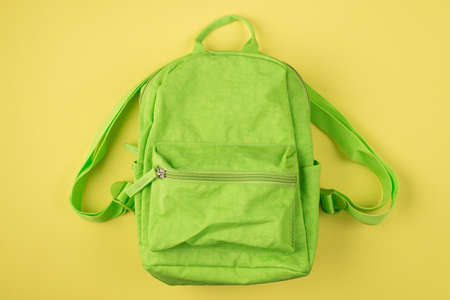 Back to school concept. Top above overhead view photo of green backpack isolated on yellow backgroundの写真素材