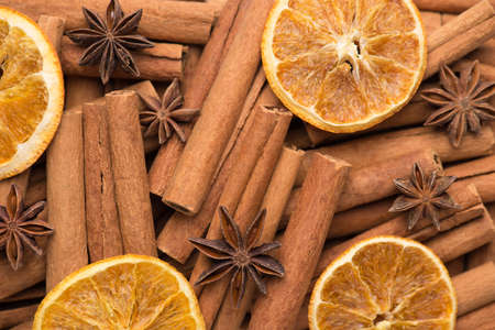 Winter festive holiday tea drink concept. Macro photo of cinnamon sticks dried orange slices and...