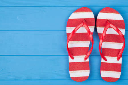 Top above overhead view close-up photo of a pair of striped flipflops placed to the right side isolated on blue wooden background with copyspaceの写真素材