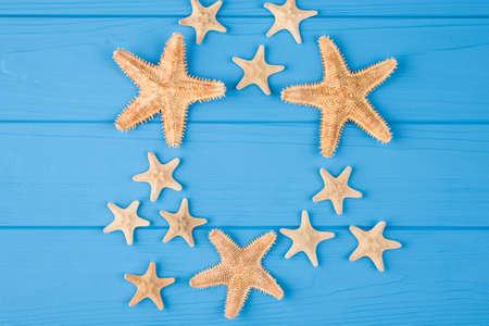 Top above overhead view close-up photo of a pattern of starfish isolated on blue wooden background...