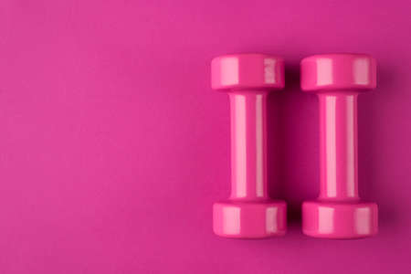 Getting fit concept. Top above overhead view photo of a pink dumbbells and a mask isolated on pink...