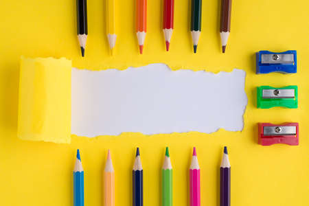 Top above overhead view photo of colorful crayons row sharpener and torn bright yellow paper over white background with copyspaceの写真素材