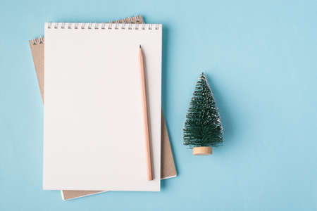 Christmas holiday concept. Top above overhead view flat lay photo of a blank notebook and a small christmas tree isolated on pastel blue color background with copyspaceの写真素材