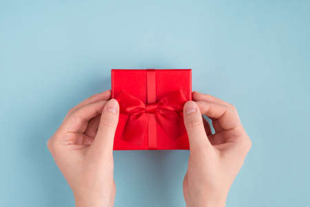 Overhead close up first person view photo of girl hands touching a bow on present box trying to open...