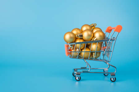 Merry Christmas concept. Side profile view photo of metal silver pushcart full of little baubles isolated over bright color blue backgroundの写真素材