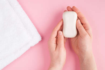 Top above overhead close up pov first person view photo of female hands holding soap isolated on pastel pink background with a white towelの写真素材