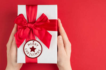 Pov top above overhead close up view photo oh female hands holding white ans red present box with round card isolated bright background with empty blank spaceの写真素材