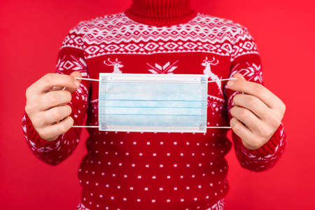 Christmas and coronavirus quarantine concept. Close up photo of men in red winter sweater with deers...