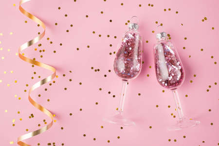 New year celebration concept. Top above overhead view photo of champagne glasses with confetti inside isolated on pastel pink background with swirl and confettiの写真素材