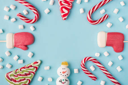 Close up overhead layout photo of funny traditional christmas candies and white marshmallow isolated pastel color background with blank space in centerの写真素材