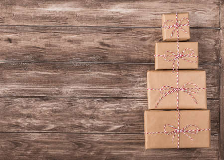 Top view photo of pile stack heap of present boxes wrapped in kraft paper on wooden brown background...