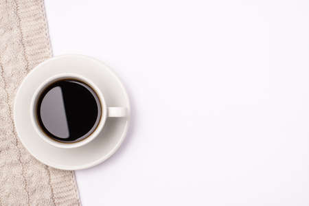 Top above close up view photo of cup of dark fresh hot coffee standing on knitted scarf on white...