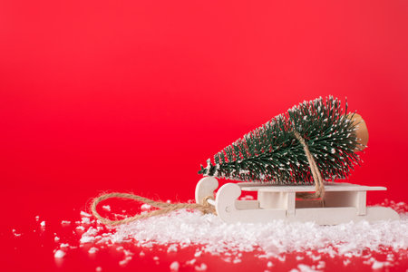 A little christmas tree on white wooden sledge isolated on red