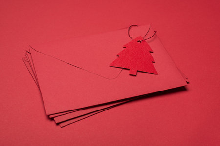 Receiving letters with wish lists concept. Close up view photo of pile of red envelopes with tag and congrats isolated red table backgroundの写真素材